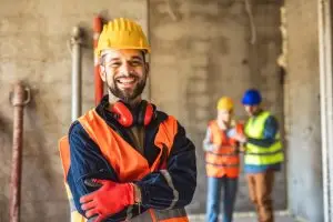 Ein lächelnder Arbeiter mit Schutzhelm und oranger Weste
