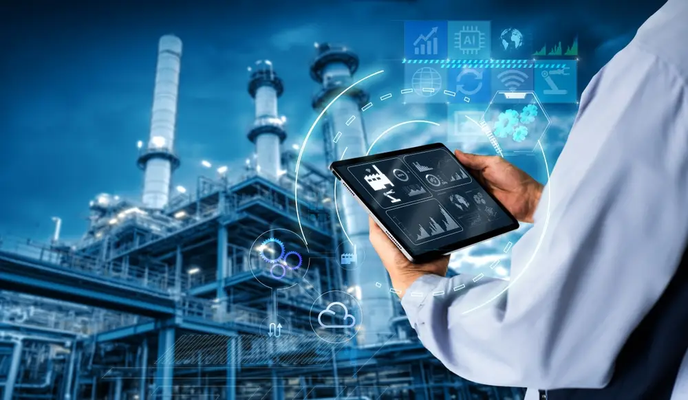 Hände die ein Tablet halten mit Industrie Steuerungssystem, Fabrik im Hintergrund.